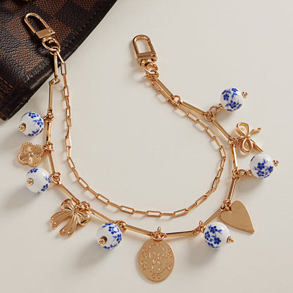 Madeline Love Gold Floral Ceramic Ball Metal Bow Heart Quatrefoil Charm Station Layered Chain Bag Charm - Bags & Wallets