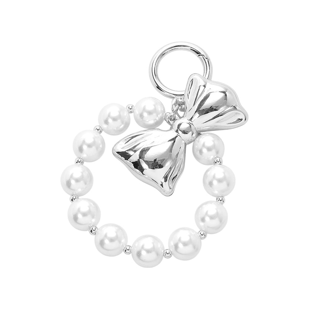 cream Rhodium Metal Bow Pearl Beaded Keychain / Bag Charm adds a touch of sophistication to your keys or bag. Made with high-quality metal and adorned with faux pearls, it brings a stylish flair to any accessory. Perfect for adding a touch of glamour to your everyday essentials. 