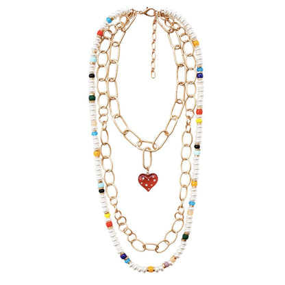 Multi Heart Pendant Accented Pearl Resin Beaded Triple Layered Necklace adds a touch of elegance and sophistication to any outfit. The heart pendant adds a sentimental touch, while the layered design creates a bold and eye-catching look. Made with high-quality materials, this necklace is both beautiful and durable.