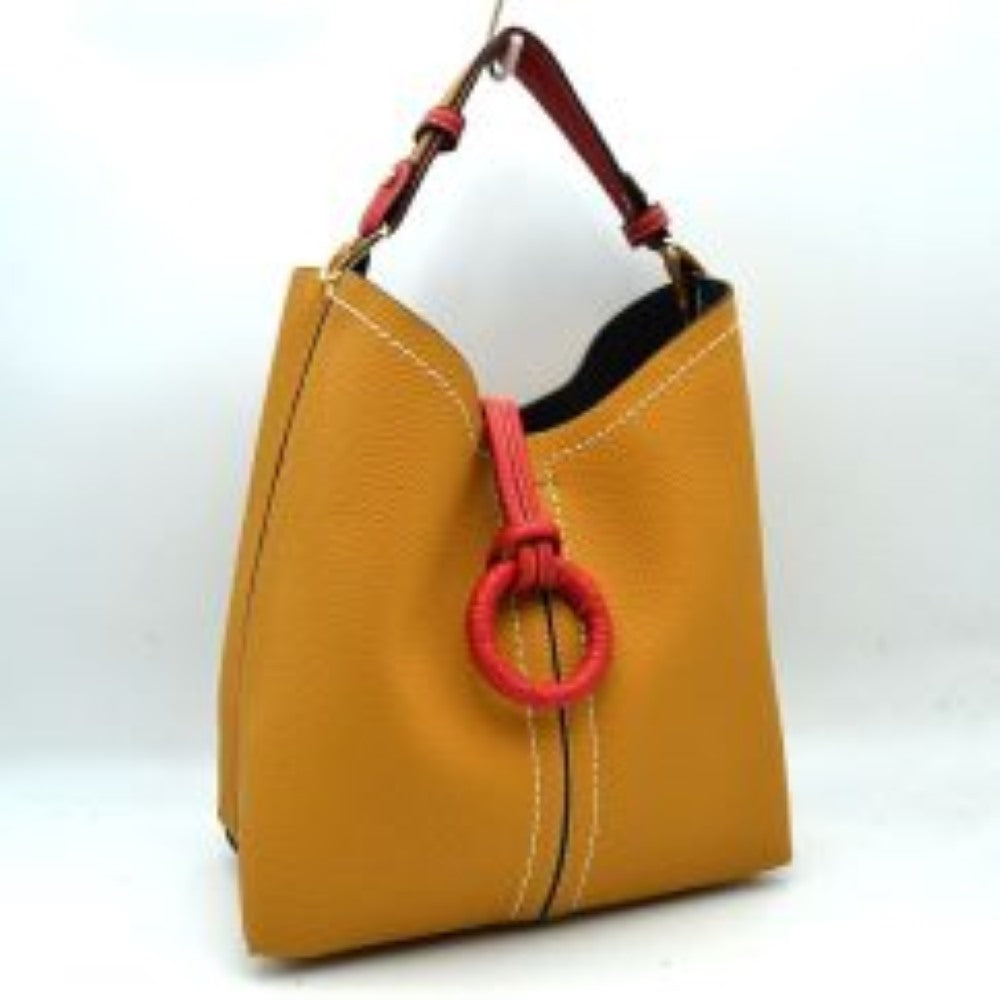 Muatrad This structured everyday bucket bag features a pebbled textured body with a distinctive curved, dip-top opening and prominent contrast stitching details along the front panel. It is designed with a singular flat top handle anchored to the sides by polished metal hardware loops for comfortable carrying. A central loop strap extends from the back to the front