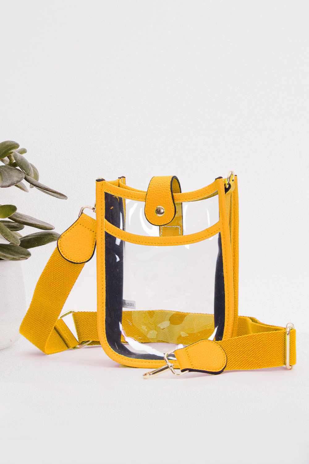 Mustard Perfect for concert season and stadium events, this clear crossbody mini bag meets all venue security requirements while keeping your essentials within reach. Crafted from durable 100% PVC, it's easy to clean and built to last through countless outings. Compact yet functional at 8" x 5.8" x 2.3", the adjustable crossbody strap sits comfortably across your body, leaving your hands free. The transparent design lets you quickly locate your phone, keys, and small valuables at a glance.