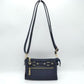 Navy Blue This functional crossbody bag is designed for organized everyday use, featuring a textured exterior equipped with multiple secure storage compartments. The front panel includes a convenient horizontal zippered pocket accented with an oversized metallic zipper pull, situated beneath a decorative horizontal band detailed with metallic studs and loops.