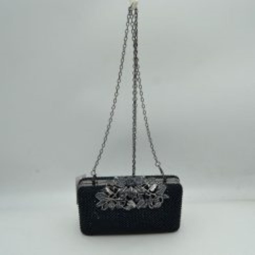 Navy-blue Designed with a rigid rectangular silhouette, this sophisticated box clutch features a meticulously textured exterior composed of small, shimmering circular studs arranged in a uniform pattern. A detailed overlay consisting of metallic leaves and floral accents spans across the top closure, creating an elegant focal point while securing the main storage compartment. A matching link chain strap attaches seamlessly to the top edges