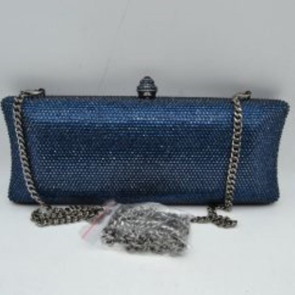 Navy This structured clutch bag features an elongated silhouette with subtly flared edges, completely covered in fine, glittering micro-embellishments that create a shimmering, textured surface suitable for elegant everyday use. The central storage compartment is securely accessed via a hard-frame opening with an ornamental, rounded top clasp. A long, slender metallic curb chain strap is permanently attached to the top loops