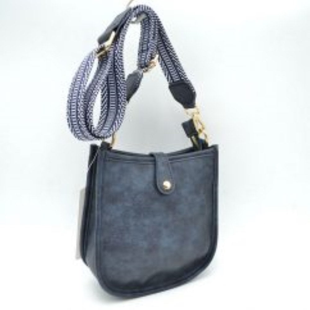 Navy blue This stylish crossbody bag presents a clean, minimalist design with a smooth exterior finish and a distinct curved, U-shaped silhouette perfect for everyday use. It features an open top main compartment equipped with a small secure tab closure that fastens at the front with a metallic snap button. Adding a striking contrast, the bag is paired with a thick, adjustable fabric strap showcasing a bold geometric pattern
