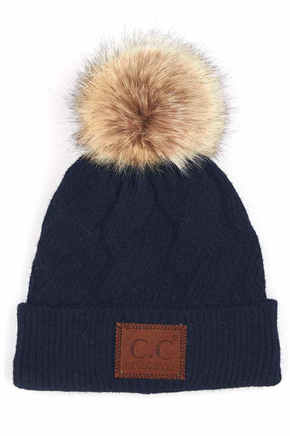 Navy The C.C Geometric Cable Knit Beanie with Pom features a beautifully textured cable pattern with eye-catching geometric detailing for a modern winter look. Finished with a soft pom-pom on top, it offers cozy warmth and effortless style for chilly days.