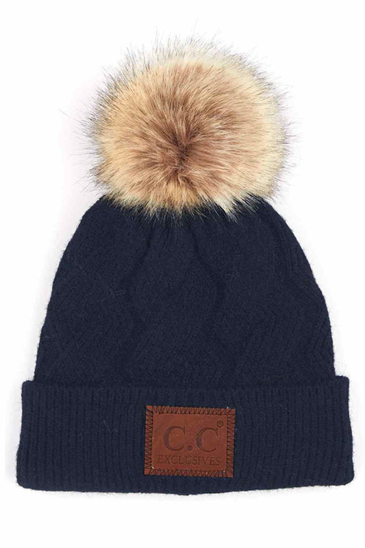 Navy The C.C Geometric Cable Knit Beanie with Pom features a beautifully textured cable pattern with eye-catching geometric detailing for a modern winter look. Finished with a soft pom-pom on top, it offers cozy warmth and effortless style for chilly days.