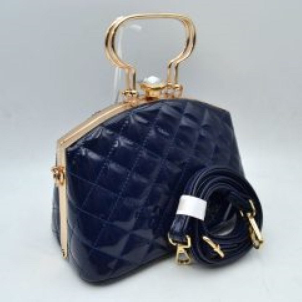 Navy-blue This structured handbag features a glossy, quilted exterior pattern that adds texturing to its rigid silhouette for everyday use. It is styled with distinctive metallic top handles and a secure upper storage compartment accessible through a solid frame opening. An ornamental crystal-like clasp sits prominently at the top closure, while side hardware rings accommodate the included matching detachable shoulder strap with metallic clips for multi-way wear.