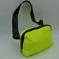 Neon green This minimalist bag features a smooth, clean design ideal for versatile everyday use. The main storage compartment is secured by a curved top zipper with dual pulls for easy access to essentials. A wide, adjustable strap extends from the sides, complete with a matching slider to easily customize the fit for comfortable carrying.