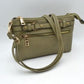 Olive This functional crossbody bag is designed for organized everyday use, featuring a textured exterior equipped with multiple secure storage compartments. The front panel includes a convenient horizontal zippered pocket accented with an oversized metallic zipper pull, situated beneath a decorative horizontal band detailed with metallic studs and loops.