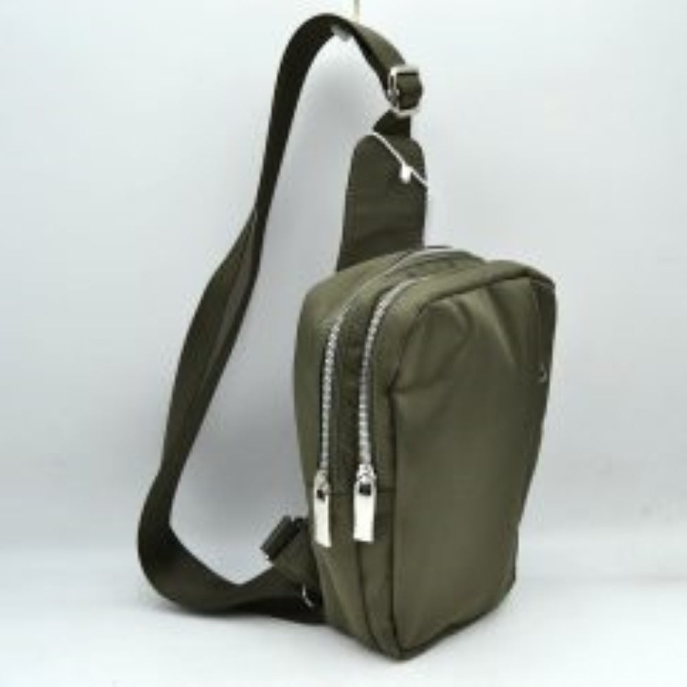 Olive This functional sling bag features a smooth, clean exterior w/ a structured vertical silhouette designed for active everyday use. It offers multiple organized storage compartments, including a primary back section and a secondary front pocket, both accessed via parallel top-curved zipper tracks w/ sleek metallic pulls. The bag is equipped w/ a wide, woven fabric shoulder strap attached to a integrated top panel and secured w/ an adjustable metallic buckle to easily customize the carrying length.
