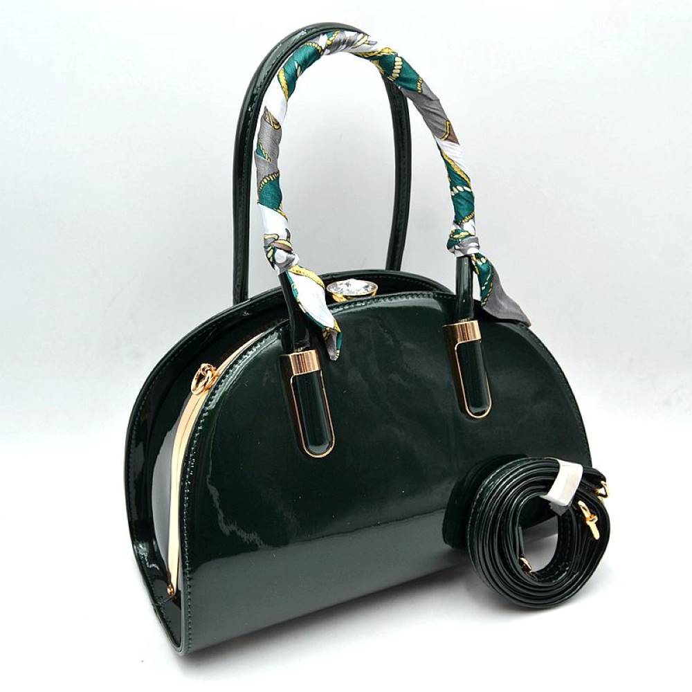 Olive This dome-shaped structured handbag features a glossy finish and an elegant curved silhouette tailored for everyday use. It is designed with dual top handles, including a patterned decorative scarf accent wrapped around the front handle, and a polished metallic framing detail. The central storage compartment secures with an ornamental top clasp, while a rolled, matching shoulder strap with metallic clips can be attached to the side hardware for versatile carrying styles.