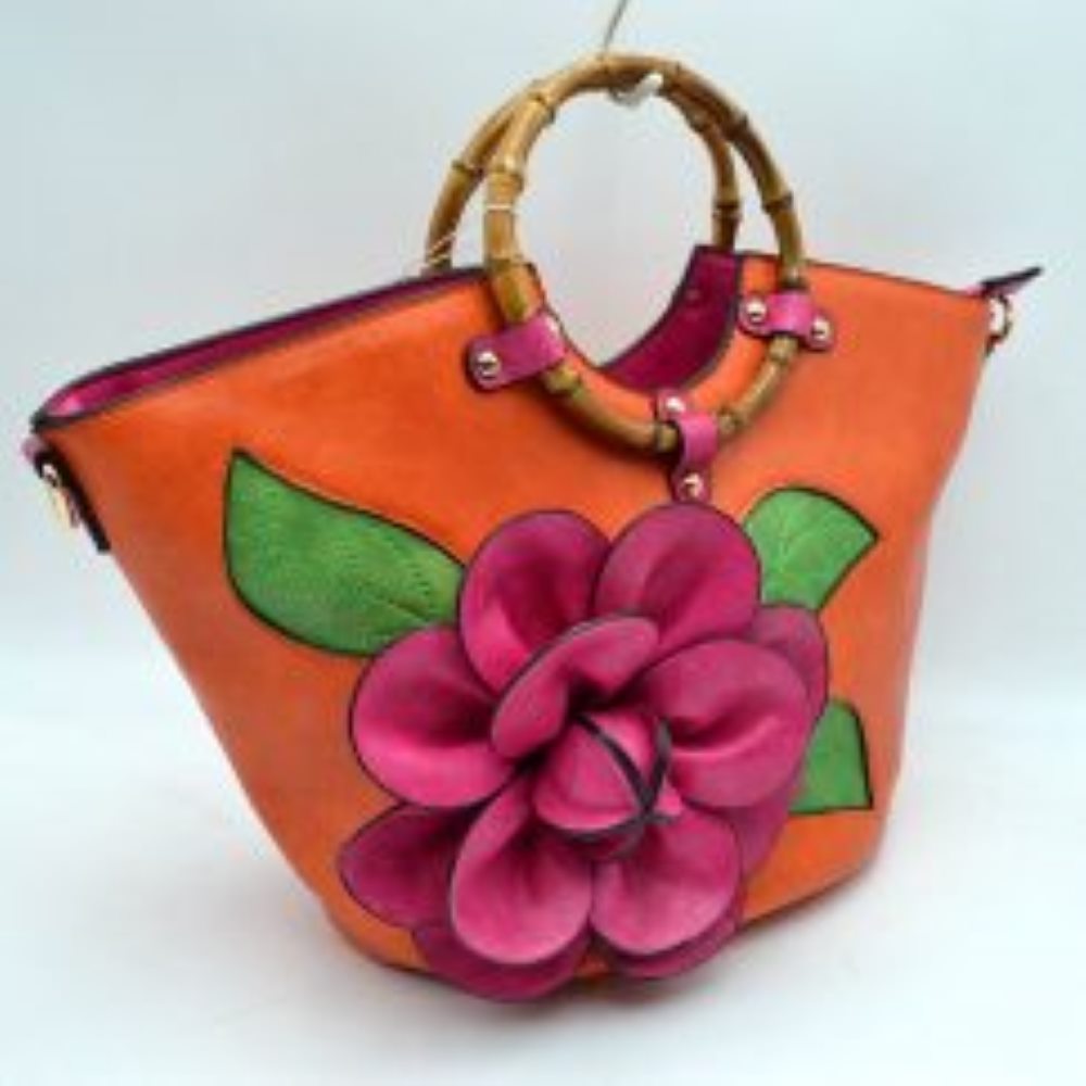 Orange This structural tote bag is designed for standout everyday use, showcasing a prominent three-dimensional floral applique paired with stitched leaf accents on the front panel. It features segmented, circular top handles secured to the curved upper rim with studded contrasting tabs. The main storage compartment opens widely at the top to reveal a vibrant interior lining