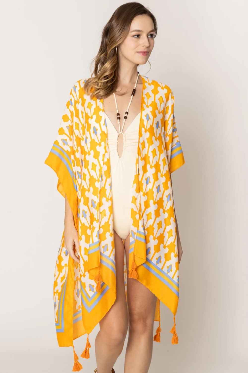 Orange Effortless elegance meets bohemian charm with this stunning tile print kimono. Crafted from lightweight 100% polyester, this versatile piece features a captivating geometric tile pattern with contrasting stripe detailing along the edges and playful tassels for added movement and flair. Perfect for layering over any outfit, this kimono drapes beautifully at 35.4" x 35.4", making it ideal for beach days, casual outings, or relaxed evenings. 