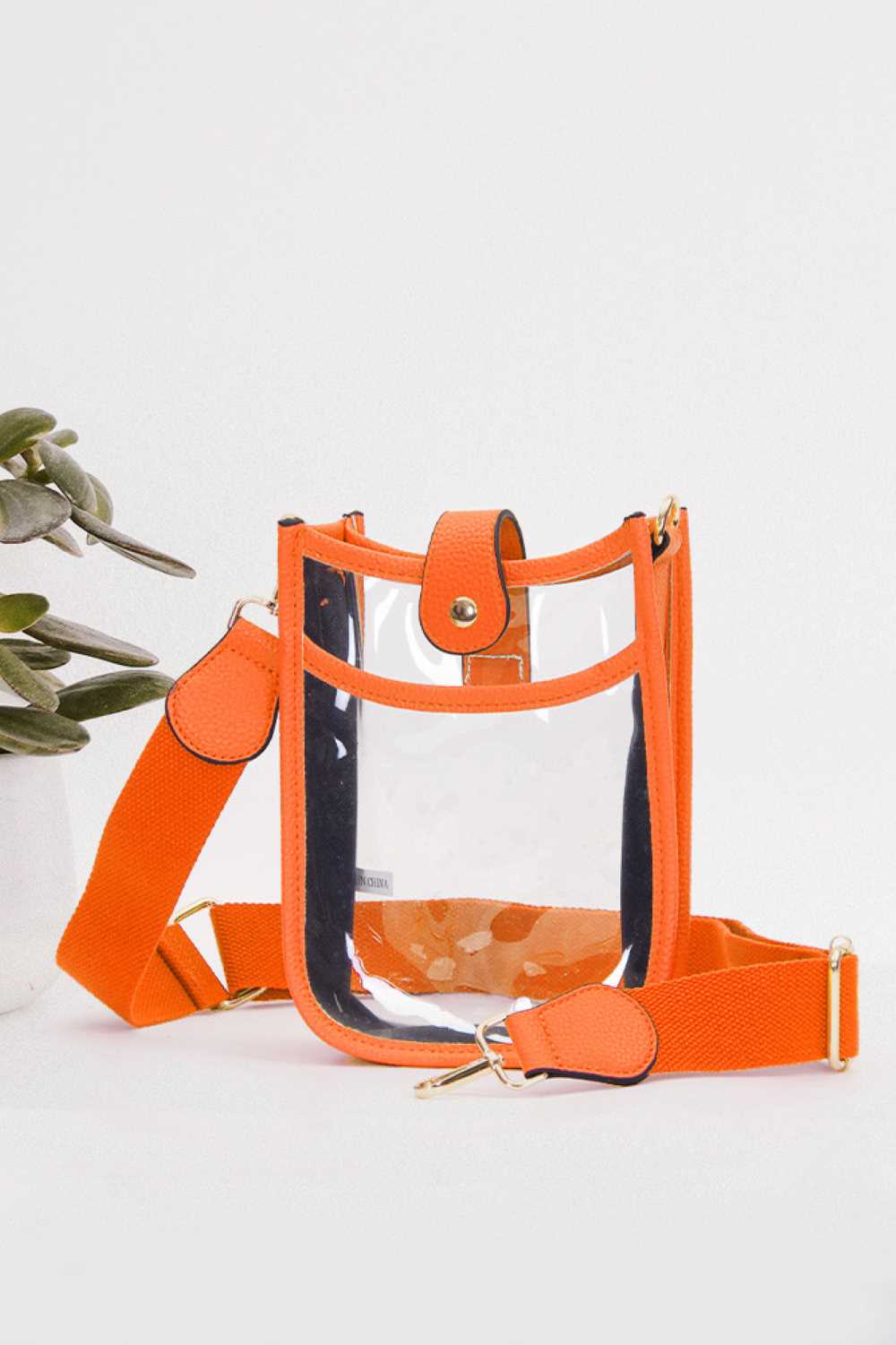 Orange Perfect for concert season and stadium events, this clear crossbody mini bag meets all venue security requirements while keeping your essentials within reach. Crafted from durable 100% PVC, it's easy to clean and built to last through countless outings. Compact yet functional at 8" x 5.8" x 2.3", the adjustable crossbody strap sits comfortably across your body, leaving your hands free. The transparent design lets you quickly locate your phone, keys, and small valuables at a glance.