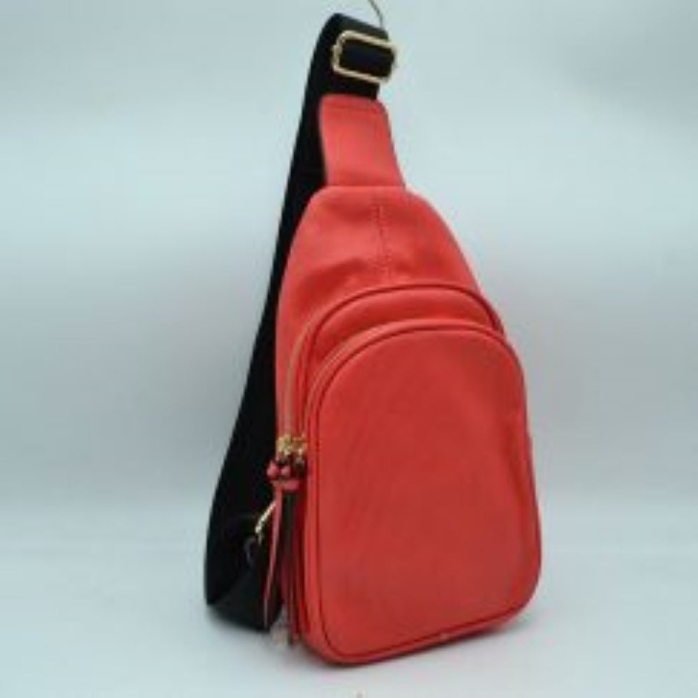 Peach This practical sling bag features a textured, finely ribbed exterior w/ a tapered silhouette designed for comfortable everyday use. It offers organized storage compartments, including a curved main zippered section and a matching smaller front zippered pouch, both enhanced by elongated vertical tassel pulls hanging from the sliders. The bag is equipped w/ a single wide fabric shoulder strap attached to a smooth top panel & secured w/ a metallic adjustment buckle to easily customize the carrying length