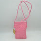 Pink This compact vertical crossbody bag is designed for everyday functionality with a distinct woven textured pattern across its body. It features a slim, continuous cord strap attached securely to the sides with visible knot details for comfortable carrying. A clean horizontal opening at the top allows effortless access to the main storage compartment