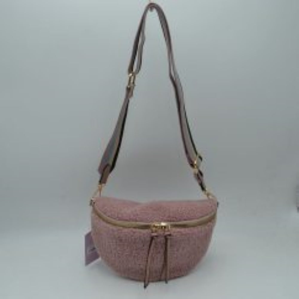 Pink This casual belt bag features a soft, textured teddy fleece exterior, offering a cozy and stylish aesthetic for active everyday use. Designed with a curved crescent silhouette, it is equipped with a secure top zipper closure detailed with dual long pulls for easy access to the main compartment. A matching, wide adjustable strap attaches via metallic clasps to side rings, allowing the bag to be comfortably worn as a crossbody, a sling bag, or around the waist.