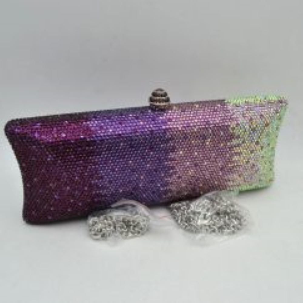 Purple-silver This structured clutch bag features an elongated silhouette with subtly flared edges, completely covered in fine, glittering micro-embellishments that create a shimmering, textured surface suitable for elegant everyday use. The central storage compartment is securely accessed via a hard-frame opening with an ornamental, rounded top clasp. A long, slender metallic curb chain strap is permanently attached to the top loops