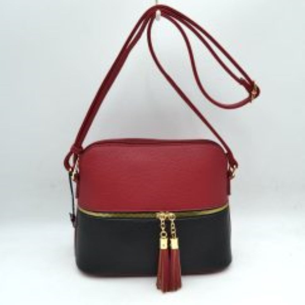 Red This everyday crossbody bag features a structured pebbled texture body with a distinct two-toned paneled design. Ideal for organized daily use, it showcases a prominent horizontal front zipper with dual gold-toned pulls, each adorned with a decorative hanging fringe tassel. The main storage compartment is paired with a matching long