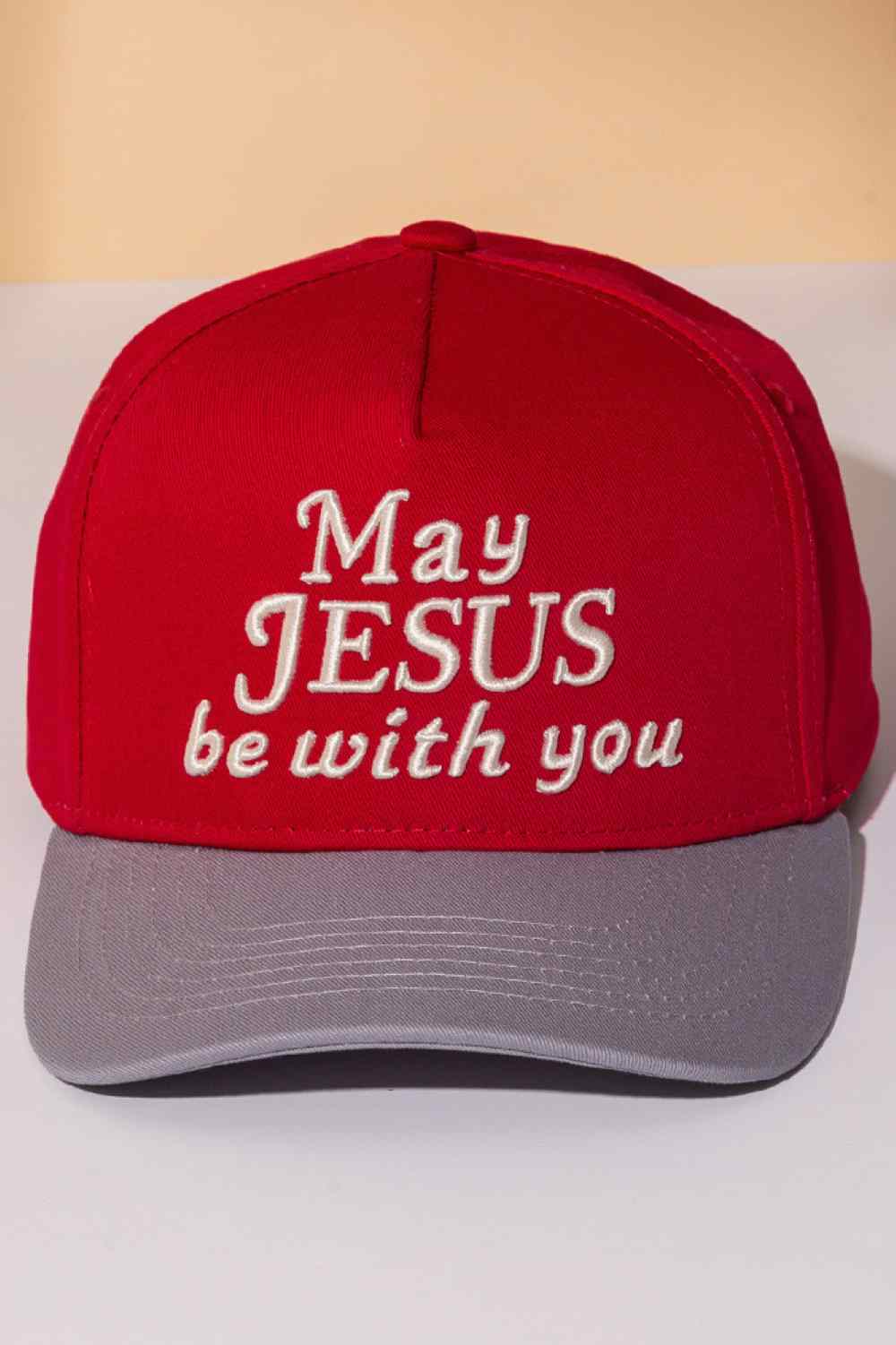 Red Classic two-tone trucker cap featuring an embroidered "MAY JESUS BE WITH YOU" message across the front. Crafted from 100% cotton for breathability and comfort, this snapback design offers one-size-fits-most versatility. Perfect for everyday wear, outdoor activities, or expressing your faith. The structured six-panel construction and mesh back panels provide durability and ventilation. An ideal accessory for those seeking meaningful style with spiritual significance.