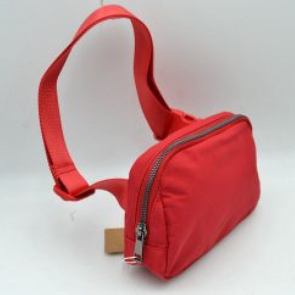 Red This minimalist bag features a smooth, clean design ideal for versatile everyday use. The main storage compartment is secured by a curved top zipper with dual pulls for easy access to essentials. A wide, adjustable strap extends from the sides, complete with a matching slider to easily customize the fit for comfortable carrying.