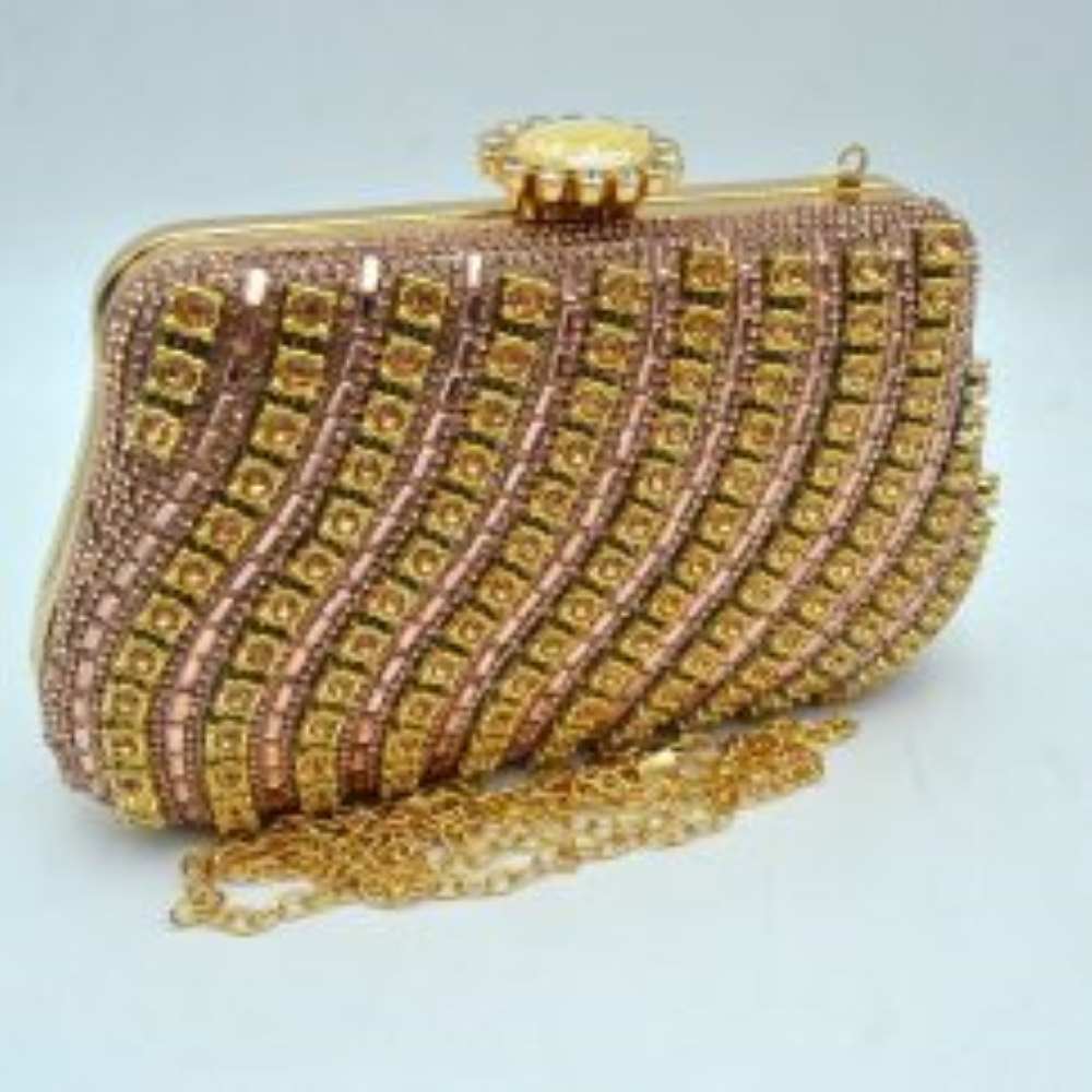 Rose-gold This luxurious evening clutch bag features a hard-shell structured body completely embellished with shimmering black rhinestones and crystals. The striking design is accented by elegant, wavy diagonal stripes of gold-toned settings framing black round stones across the front panel. Ideal for formal gatherings, weddings, or special galas, the main compartment is secured by a polished gold-toned top frame with an ornate, jewel-encrusted crown clasp closure.