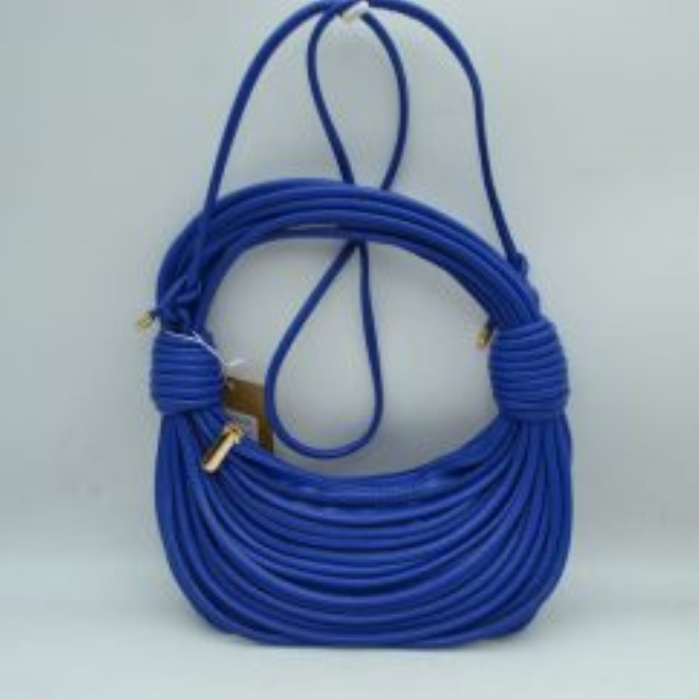 Royal blue This avant-garde shoulder bag features a unique crescent silhouette crafted from layered, parallel tubular cords in a classic black finish, making it a true statement piece. The sculptural design is highlighted by thick, wrapped knot accents on each side that transition seamlessly into a structured, integrated top arch handle. Nestled within the curved opening is a secure gold-tone zipper closure to keep your essentials safe, while a long, slim matching strap allows for a comfortable.