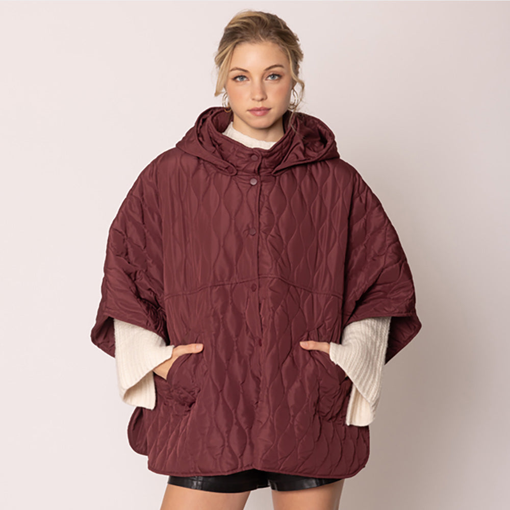 Burgundy Stylish quilted cape jacket featuring a relaxed silhouette, button-up front, and attached hood for added comfort. Perfect for layering during cooler seasons, this versatile outerwear piece combines warmth with a modern, minimalistic design for effortless everyday style.