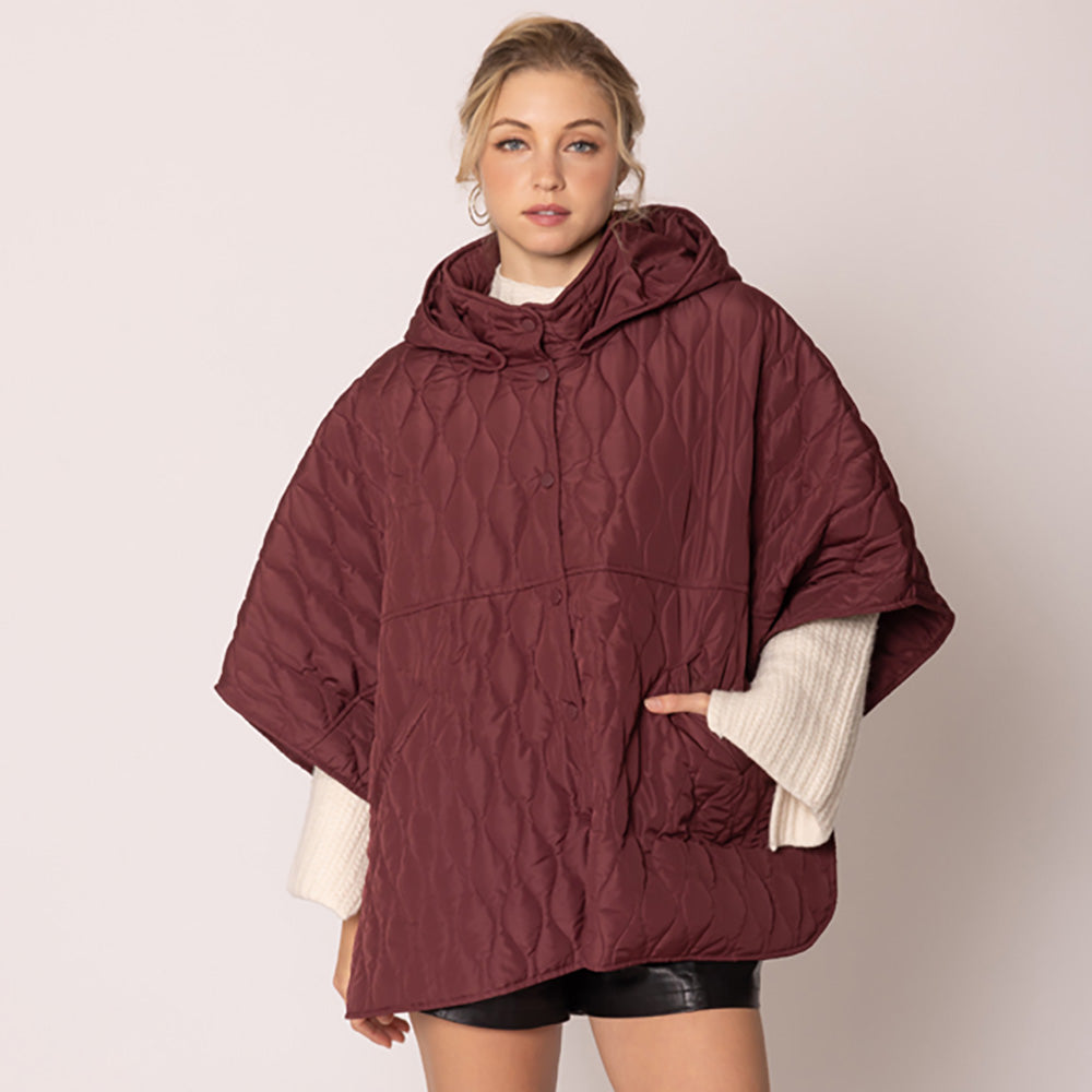 Burgundy Stylish quilted cape jacket featuring a relaxed silhouette, button-up front, and attached hood for added comfort. Perfect for layering during cooler seasons, this versatile outerwear piece combines warmth with a modern, minimalistic design for effortless everyday style.