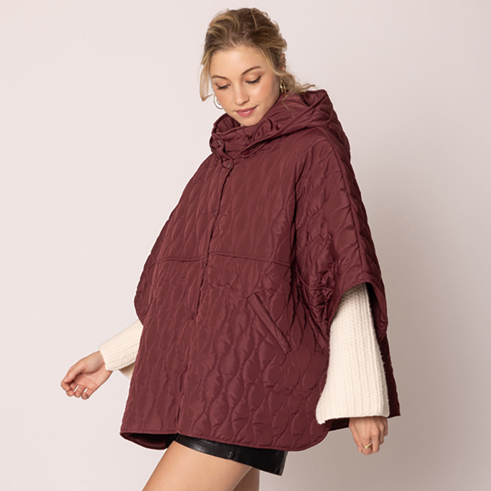 Burgundy Stylish quilted cape jacket featuring a relaxed silhouette, button-up front, and attached hood for added comfort. Perfect for layering during cooler seasons, this versatile outerwear piece combines warmth with a modern, minimalistic design for effortless everyday style.