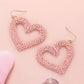 Seed Beaded Open Heart Dangle Earrings are handcrafted with delicate beads, forming an open heart that dangles elegantly. The intricate design adds a touch of romance to any outfit. These earrings are versatile and can be worn for any occasion, perfect for any fashion-forward individual. 