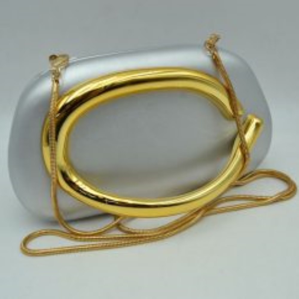 Silver This structured, hard shell clutch bag functions as an elegant accessory for everyday use or special occasions, featuring a smooth matte surface. A large, prominent metallic ring handle anchors the front design, offering a secure hand-held grip. For alternative carrying styles, the bag is equipped with a detachable metallic snake chain strap that secures to the top corners with lobster claw clasps, providing functional storage in a compact, rigid silhouette.