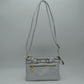 Silver This functional crossbody bag is designed for organized everyday use, featuring a textured exterior equipped with multiple secure storage compartments. The front panel includes a convenient horizontal zippered pocket accented with an oversized metallic zipper pull, situated beneath a decorative horizontal band detailed with metallic studs and loops.