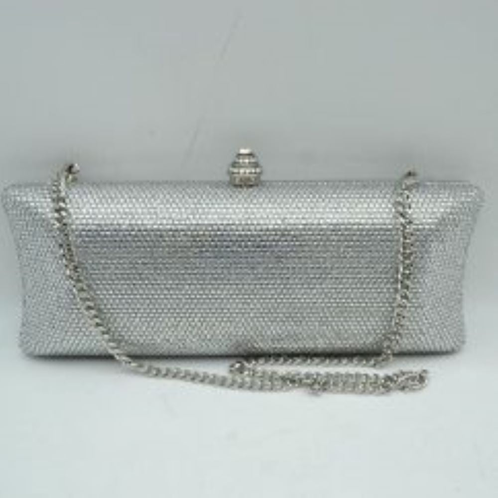 Silver This structured clutch bag features an elongated silhouette with subtly flared edges, completely covered in fine, glittering micro-embellishments that create a shimmering, textured surface suitable for elegant everyday use. The central storage compartment is securely accessed via a hard-frame opening with an ornamental, rounded top clasp. A long, slender metallic curb chain strap is permanently attached to the top loops