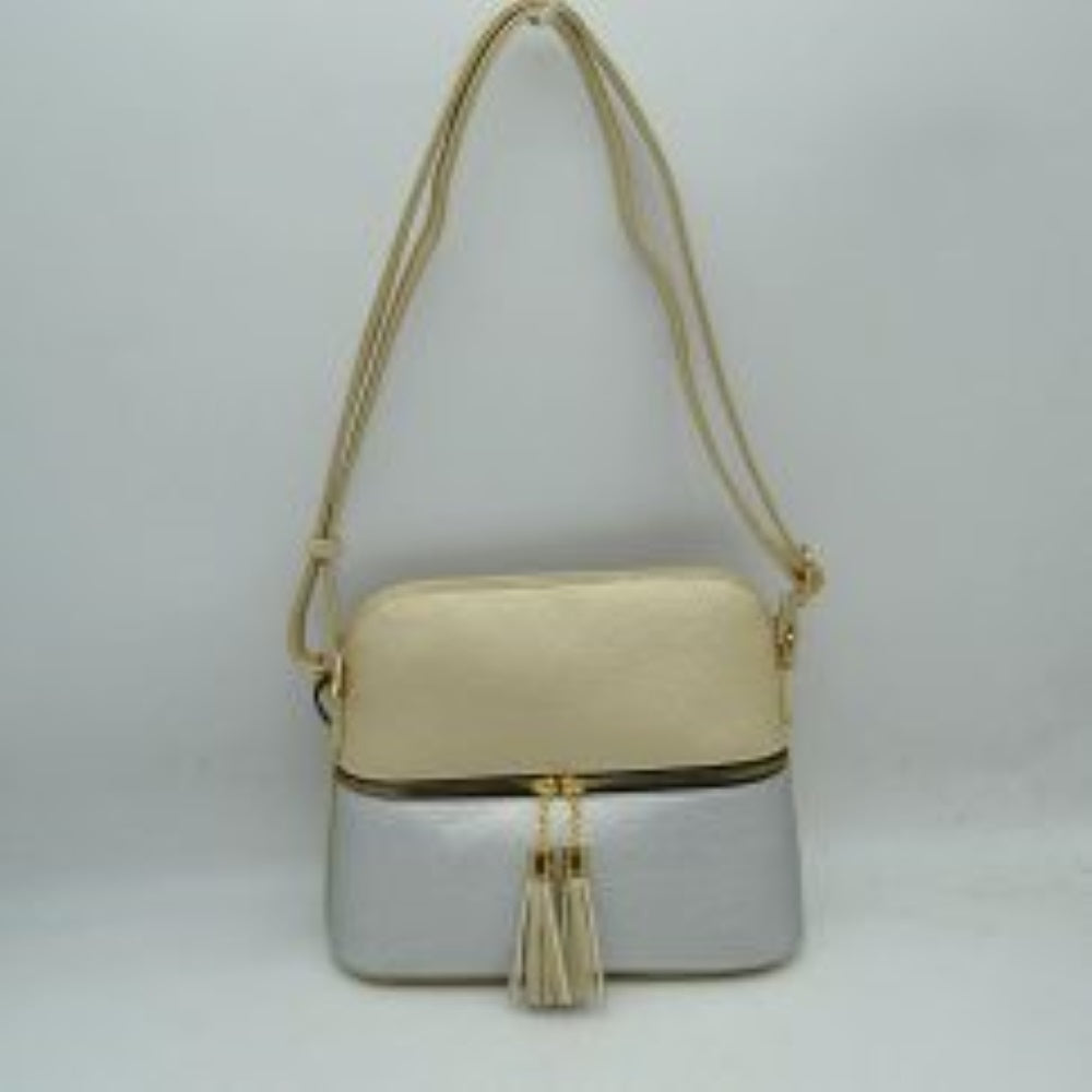 Silver This everyday crossbody bag features a structured pebbled texture body with a distinct two-toned paneled design. Ideal for organized daily use, it showcases a prominent horizontal front zipper with dual gold-toned pulls, each adorned with a decorative hanging fringe tassel. The main storage compartment is paired with a matching long