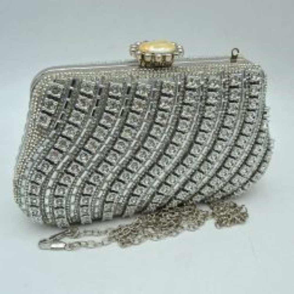 Silver This luxurious evening clutch bag features a hard-shell structured body completely embellished with shimmering black rhinestones and crystals. The striking design is accented by elegant, wavy diagonal stripes of gold-toned settings framing black round stones across the front panel. Ideal for formal gatherings, weddings, or special galas, the main compartment is secured by a polished gold-toned top frame with an ornate, jewel-encrusted crown clasp closure.