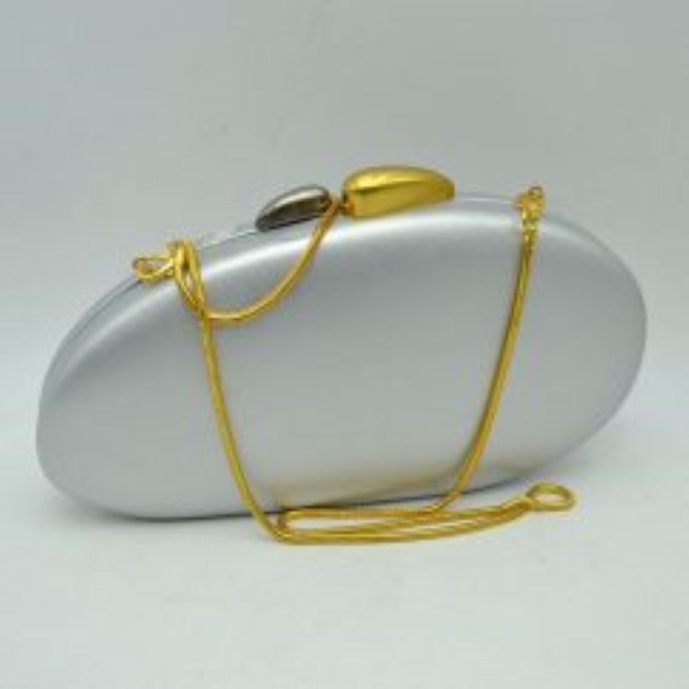 Silver This structured hardcase clutch bag features a smooth, rounded oval silhouette designed as a sleek accessory for everyday use. Its single interior storage compartment is secured with a rigid frame closure, accented at the top by a distinctive, asymmetrical two-tone sculptural clasp. A slender, matching metallic snake chain strap connects to small loop anchors on either side via clasp attachments, offering convenient options for hands-free shoulder or crossbody styling.