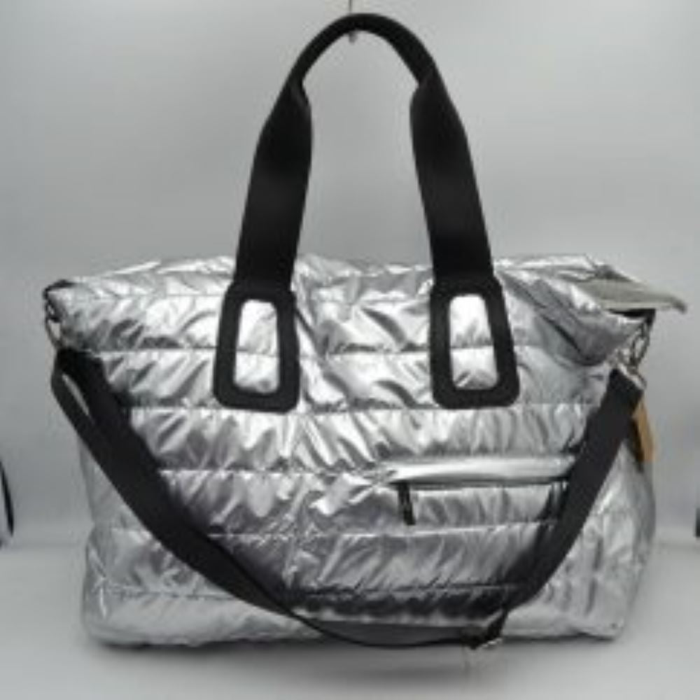 Silver Upgrade your travel gear with this exceptionally spacious, lightweight weekender duffel bag, perfect for overnight trips, gym sessions, or casual weekend getaways. Featuring a stylish horizontally quilted puffer design, this bag combines a cozy, modern aesthetic with highly practical function. It is designed with wide, durable webbed top handles for a comfortable grip, alongside a matching adjustable and detachable shoulder strap secured by polished metallic clasps for easy hands-free carrying.