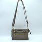 Steel This functional crossbody bag is designed for organized everyday use, featuring a textured exterior equipped with multiple secure storage compartments. The front panel includes a convenient horizontal zippered pocket accented with an oversized metallic zipper pull, situated beneath a decorative horizontal band detailed with metallic studs and loops.