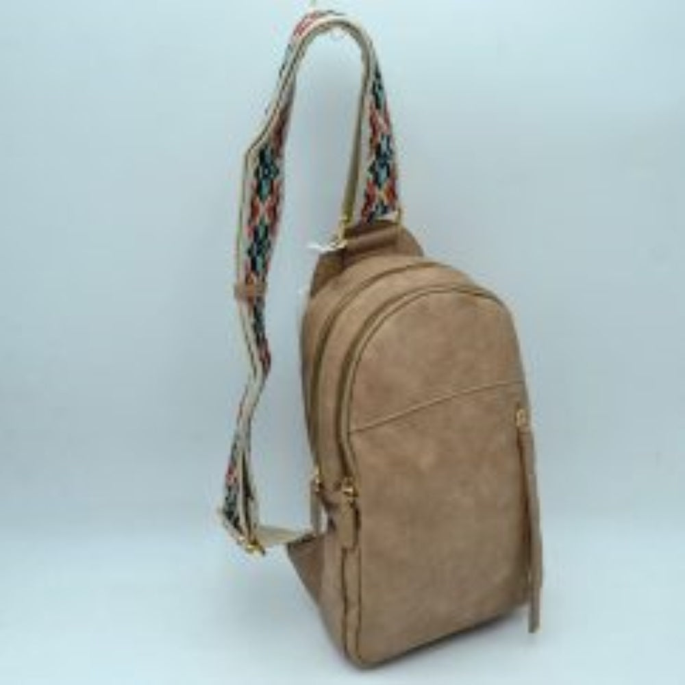 Steel This multi-compartment sling backpack features a smooth texture and a contoured, upright silhouette optimized for daily use. It offers practical storage compartments, consisting of two tiered main sections with independent gold-tone zipper closures alongside a side-access vertical zippered pocket. A distinctive, wide fabric shoulder strap decorated with a detailed geometric woven pattern connects securely to the top and bottom anchors
