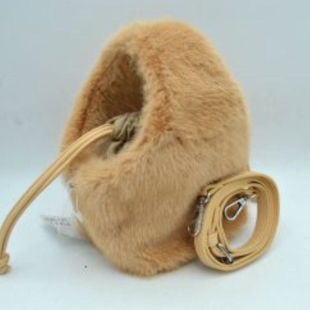Tan This unique everyday bucket handbag features a soft, high-pile plush exterior that brings a cozy, tactile texture to your accessory collection. Designed with a rounded, structured silhouette, it features a central main storage compartment accessed through a flexible top opening with a drawstring cord tie for secure closure. For versatile carrying options, the bag includes an integrated top cutout handle alongside a separate, detachable shoulder strap equipped with metallic clasps.