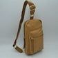 Tan This functional sling bag features a textured, grained finish exterior designed for streamlined everyday use. It offers multiple practical storage compartments, including a curved main section secured by a prominent metallic zipper track and a secondary front pocket with a horizontal zipper and an elongated pull tab. The bag is equipped with a single wide shoulder strap that attaches via a rectangular loop and incorporates an adjustable metallic buckle to easily customize the carrying length.