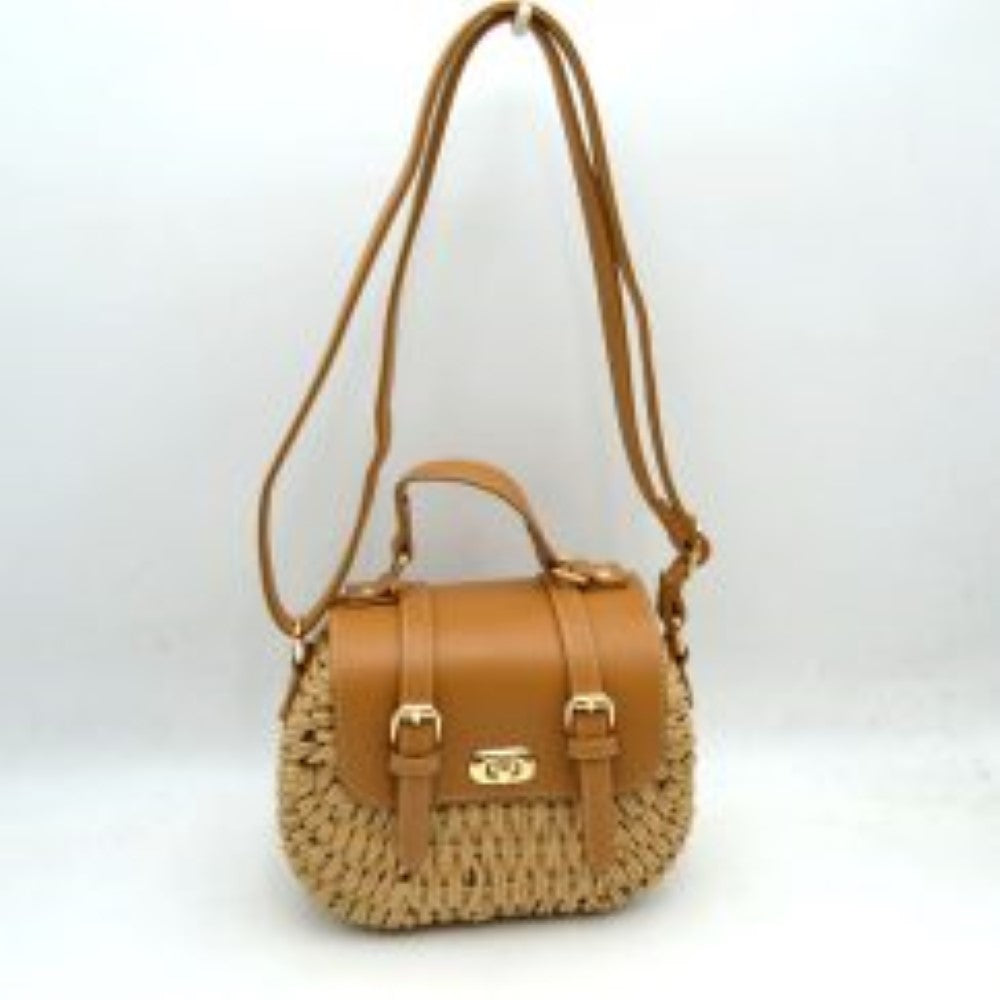 Tan This charming satchel features a woven straw body paired with a smooth faux leather foldover flap, making it a stylish choice for warm-weather outings. It is detailed with dual decorative buckle straps on the front along with a secure gold-tone turn-lock closure. Designed for versatile wear, it includes a sturdy top handle for handheld carrying and a long, adjustable shoulder strap for comfortable hands-free crossbody or shoulder styling.