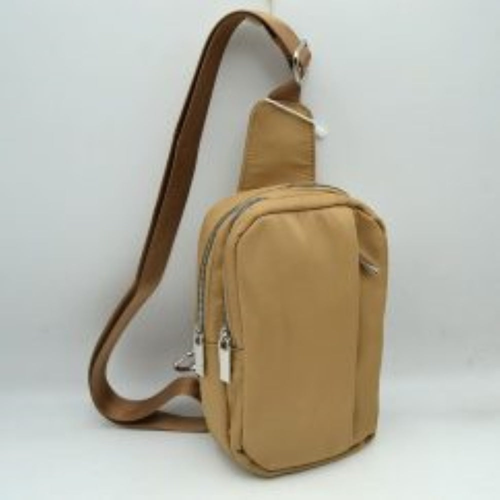 Taupe This functional sling bag features a smooth, clean exterior w/ a structured vertical silhouette designed for active everyday use. It offers multiple organized storage compartments, including a primary back section and a secondary front pocket, both accessed via parallel top-curved zipper tracks w/ sleek metallic pulls. The bag is equipped w/ a wide, woven fabric shoulder strap attached to a integrated top panel and secured w/ an adjustable metallic buckle to easily customize the carrying length.
