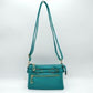 Turquoise This functional crossbody bag is designed for organized everyday use, featuring a textured exterior equipped with multiple secure storage compartments. The front panel includes a convenient horizontal zippered pocket accented with an oversized metallic zipper pull, situated beneath a decorative horizontal band detailed with metallic studs and loops.