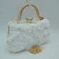 White Make an elegant impression at your next formal event with this stunning evening clutch bag. The exterior features a beautiful arrangement of multi-dimensional, textured rosettes that create a soft floral pattern over a smooth base fabric. A polished, metallic top handle arches elegantly over the structured frame, while a prominent rhinestone-encrusted clasp closure sits at the top to secure your essentials with a touch of brilliant sparkle. Perfect for weddings, galas