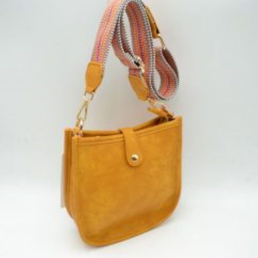 Yellow This stylish crossbody bag presents a clean, minimalist design with a smooth exterior finish and a distinct curved, U-shaped silhouette perfect for everyday use. It features an open top main compartment equipped with a small secure tab closure that fastens at the front with a metallic snap button. Adding a striking contrast, the bag is paired with a thick, adjustable fabric strap showcasing a bold geometric pattern