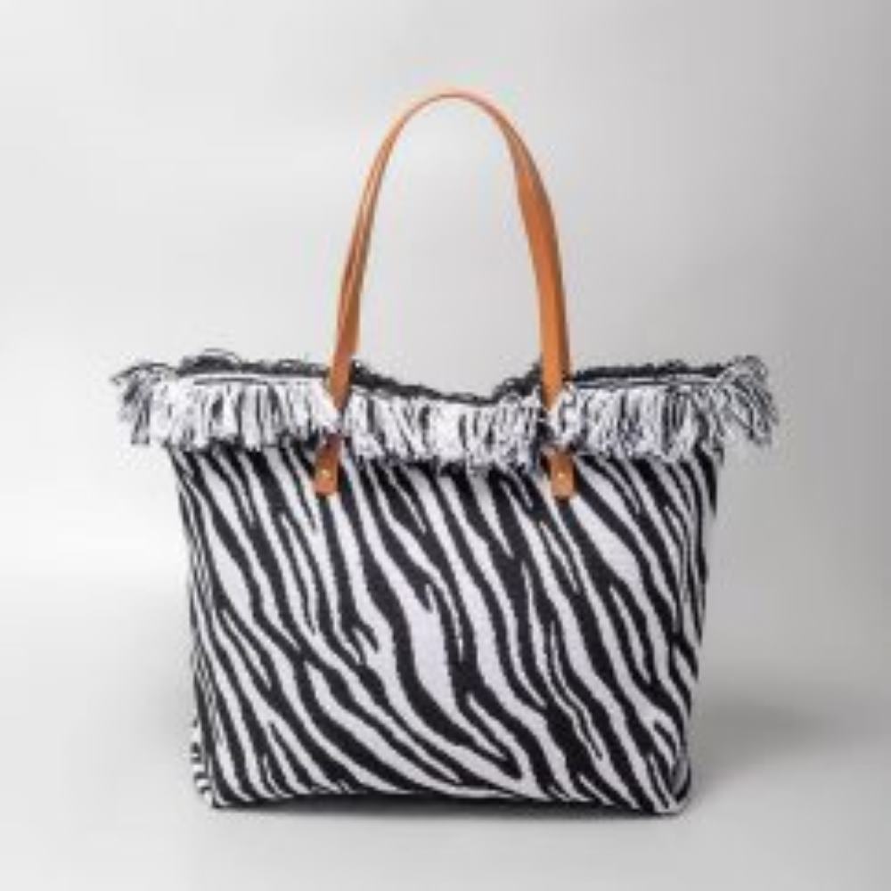 Zebra This spacious tote bag features a finely textured main body adorned with an eye-catching, voluminous fringe trim entirely wrapping around the upper opening. Designed for versatile everyday use, the bag is equipped with dual flat shoulder straps anchored securely to the front and back panels by metallic rivets.