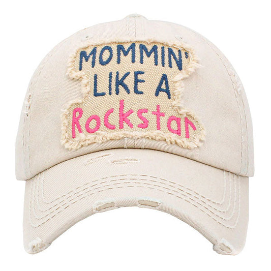 Beige Mommin Like A Rockstar Message Vintage Baseball Cap. Fun cool vintage cap perfect for the mommin who is in Charge! Perfect for walks in sun or rain, great for a bad hair day. Soft textured, embroidered message and distressed contrast stitching baseball cap with fun statement will become your favorite cap. Velcro Adjustable Back